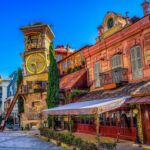 A vibrant and colorful view of the Clock Tower in Tbilisi, Georgia, with its unique architecture and charming surroundings under a bright blue sky.