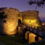 Night view of Belgrade Fortress with illuminated stone walls and a wooden bridge at Kalemegdan Park in Belgrade, Serbia.