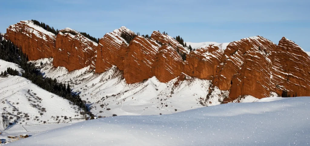 Snow-covered red rock formations of Djety-Oguz Gorge, also known as "Seven Bulls," in Kyrgyzstan.